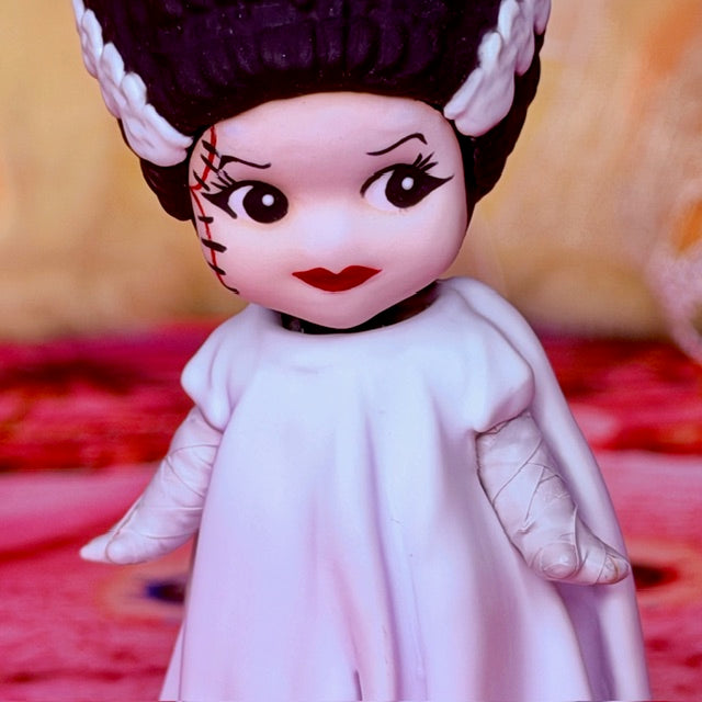 Custom vinyl doll face with dark purple hair, white veil, red lips, stitched makeup.
