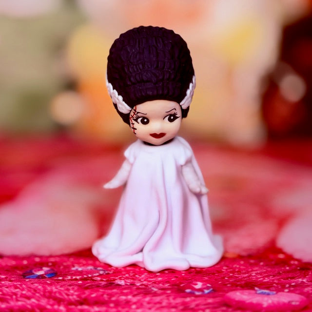 Custom vinyl doll figure with dark purple bob hair and white bride dress, seated.