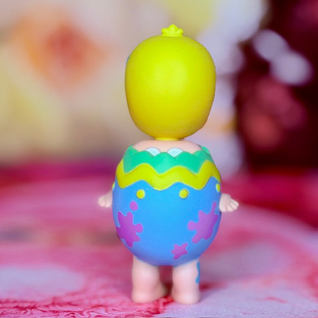 Easter collectible figure with yellow head emerging from purple hatching egg, green top