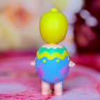 Easter collectible figure with yellow head emerging from purple hatching egg, green top