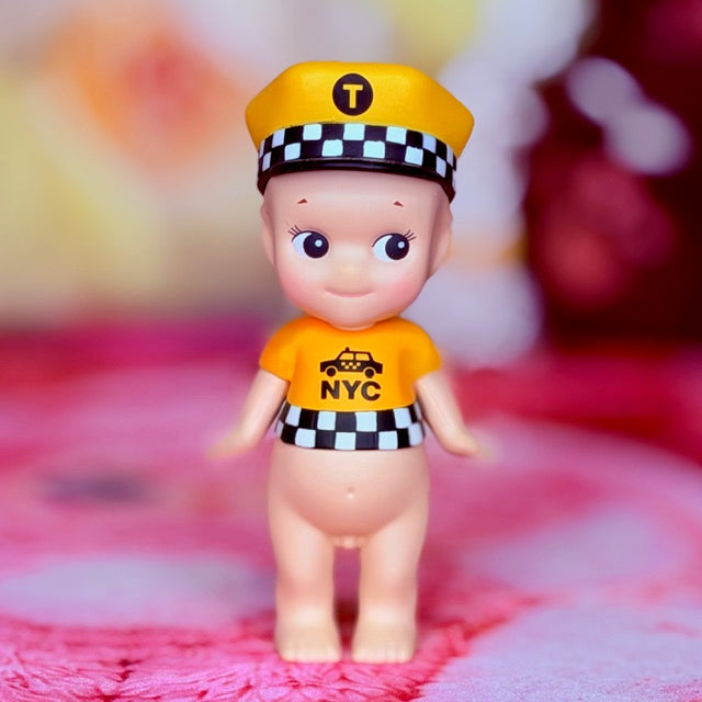 Yellow taxi-themed vinyl figure with 'NYC' shirt and checkered hat