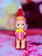 Duck Santa’s Little Helper figurine holding a yellow gift, front view