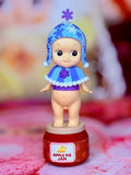 Sonny Angel figure in blue snowy hat and purple dress on Apple Pie Jam base