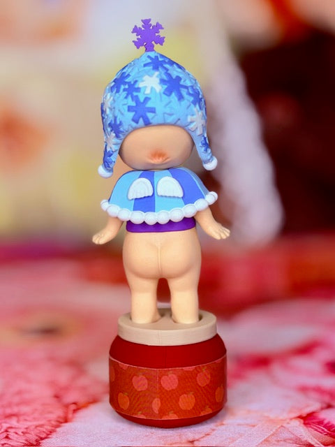 Sonny Angel snowy sky series figure with blue hat and purple dress on jar base