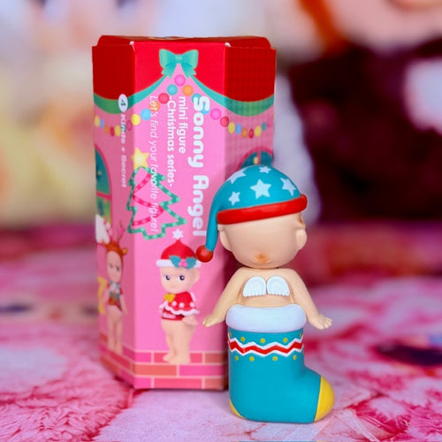 Sonny Angel Christmas stocking figure in blue and red, beside pink box packaging