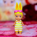 Yellow rabbit figurine with heart ear accessories and striped romper overalls