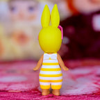 Yellow rabbit figurine with pink ear accents and striped romper overalls