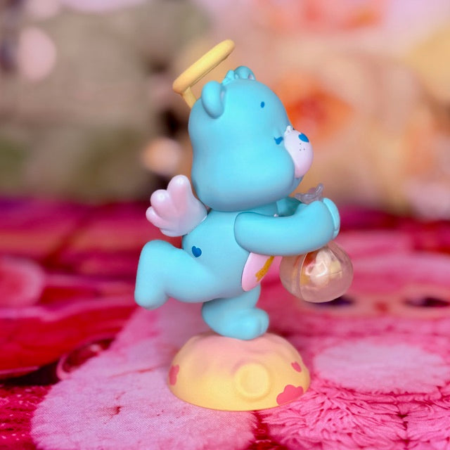 Side view of the blue Wish Bear figurine holding a clear orb above a heart-patterned base