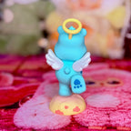 Back of the Wish Bear figurine with white wings, yellow halo, and blue paw print
