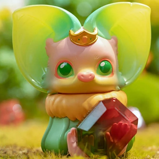 Yellow-green winged collectible figure holding a red heart-shaped book, seated on grass