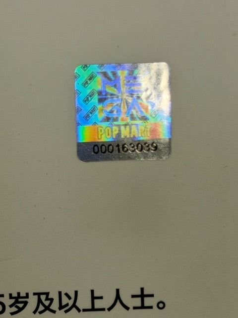 Holographic POP MART sticker label with colorful pattern and tiny code text